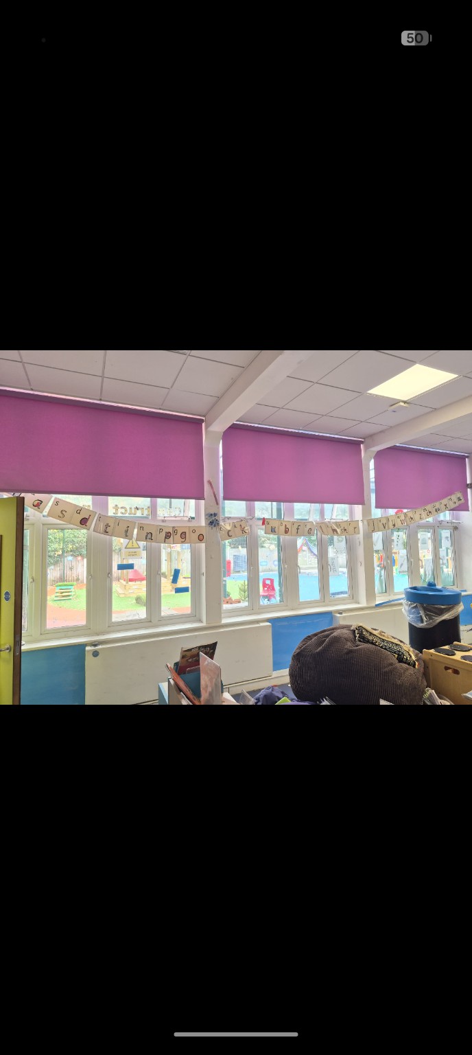 Pink roller blinds across classroom windows