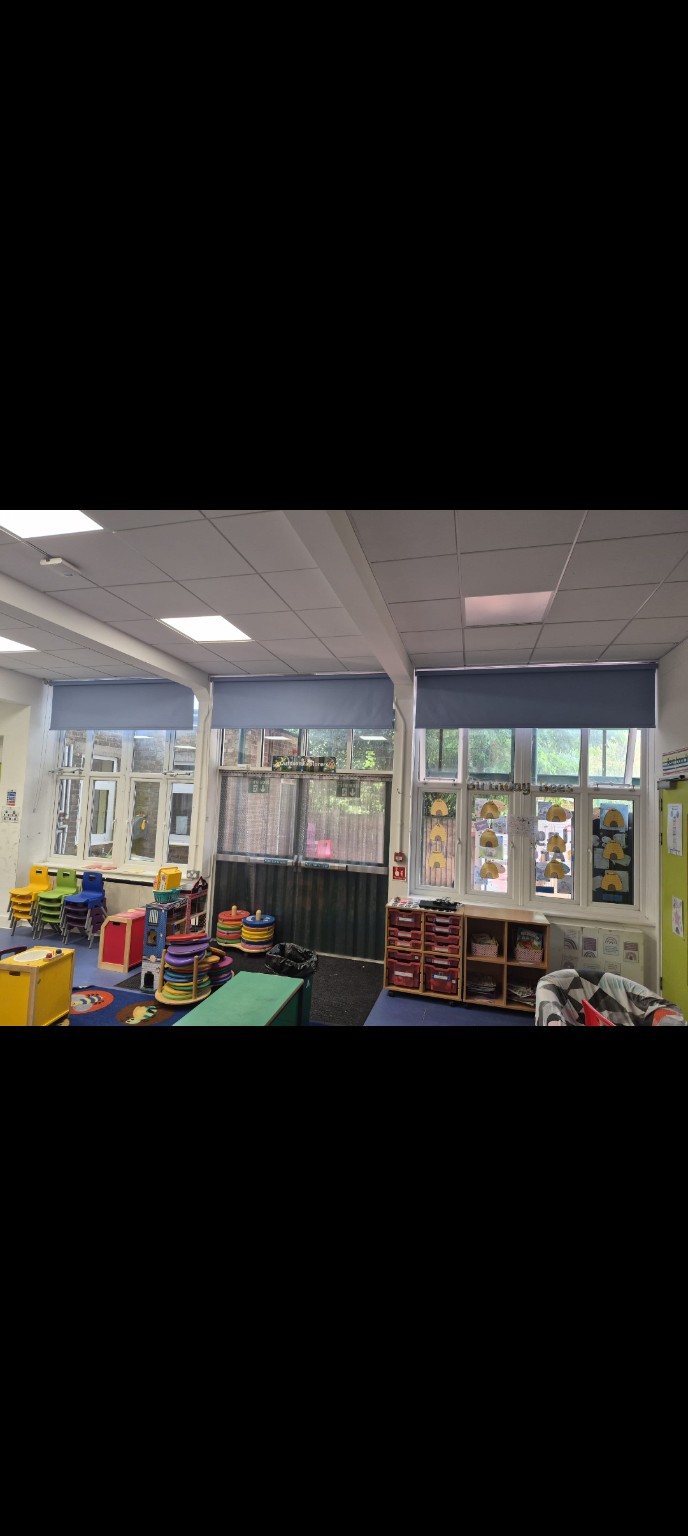 Grey roller blinds across classroom windows